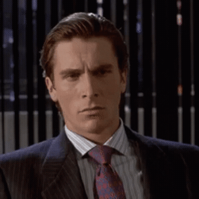 A Man In A Suit And Tie Is Looking At The Camera GIF