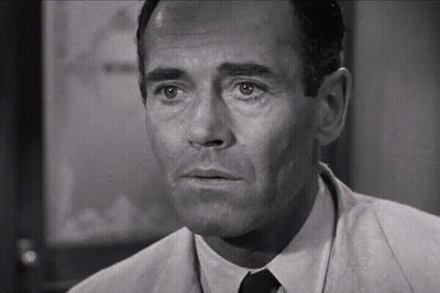 A Man In A Suit And Tie Is Looking At The Camera GIF