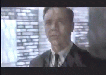 A Man In A Suit And Tie Is Looking At The Camera GIF
