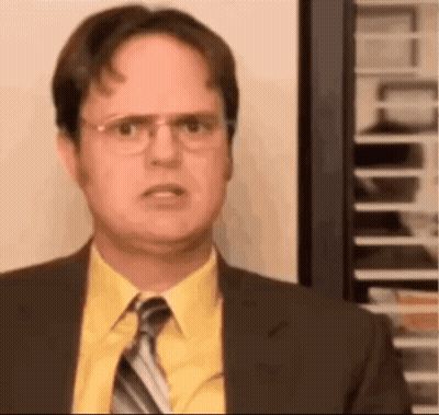 A Man In A Suit And Tie Is Looking At The Camera . GIF