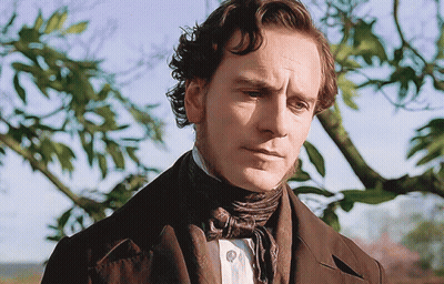 A Man In A Suit And Tie Is Looking At The Camera GIF