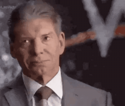 A Man In A Suit And Tie Is Looking At The Camera With A Blurred Background . GIF