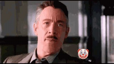 A Man In A Suit And Tie Is Looking At The Camera With A Clown Face On His Chest . GIF