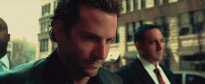 A Man In A Suit And Tie Is Looking Down At Something GIF