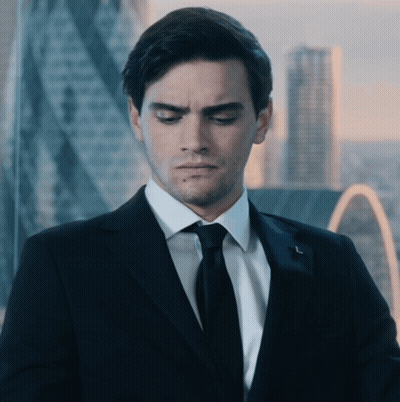 A Man In A Suit And Tie Is Looking Down With A City In The Background GIF