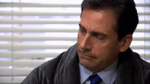 A Man In A Suit And Tie Is Looking Down GIF