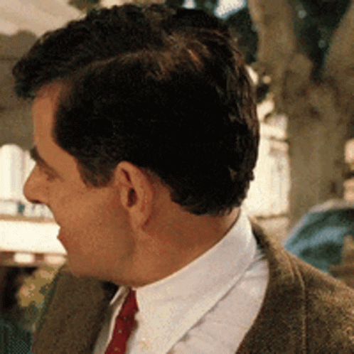 A Man In A Suit And Tie Is Looking To His Left GIF