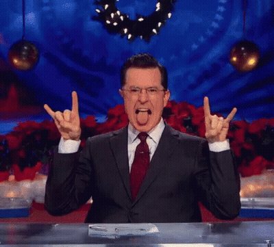 A Man In A Suit And Tie Is Making A Devil Horns Sign With His Hands GIF
