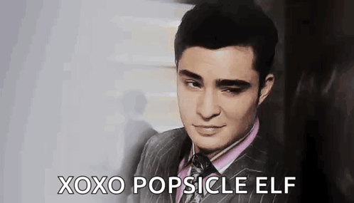 A Man In A Suit And Tie Is Making A Face And Saying `` Xoxo Popsicle Elf '' . GIF