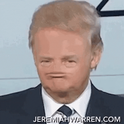 A Man In A Suit And Tie Is Making A Face . GIF