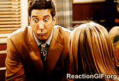 A Man In A Suit And Tie Is Making A Face In Front Of A Woman GIF