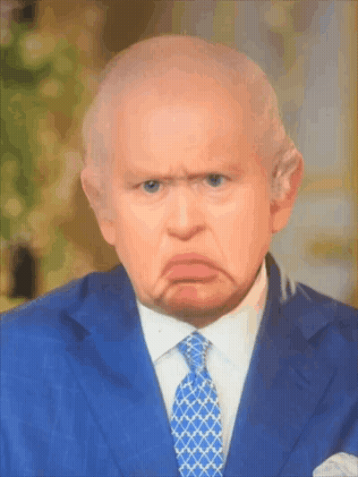 A Man In A Suit And Tie Is Making A Face GIF