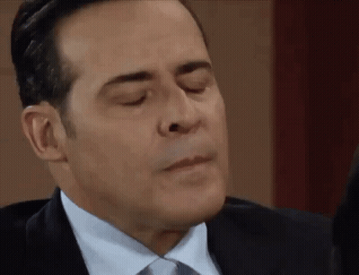 A Man In A Suit And Tie Is Making A Face With His Eyes Closed . GIF
