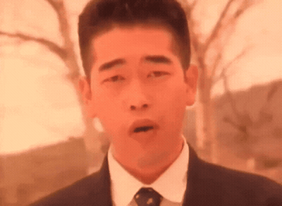 A Man In A Suit And Tie Is Making A Face With His Mouth Open . GIF