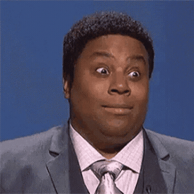 A Man In A Suit And Tie Is Making A Funny Face And Looking At The Camera . GIF