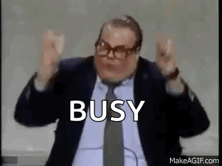 A Man In A Suit And Tie Is Making A Funny Face And Saying Busy . GIF