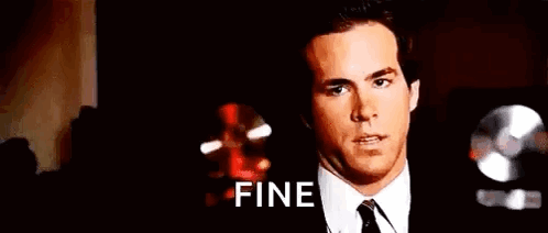 A Man In A Suit And Tie Is Making A Funny Face And Saying Fine . GIF