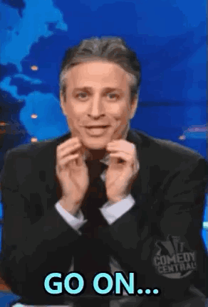 A Man In A Suit And Tie Is Making A Funny Face And Saying `` Go On '' . GIF