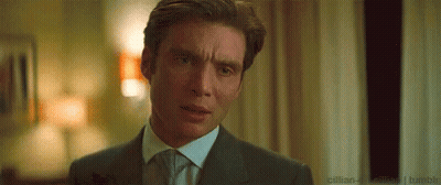 A Man In A Suit And Tie Is Making A Funny Face In A Room . GIF