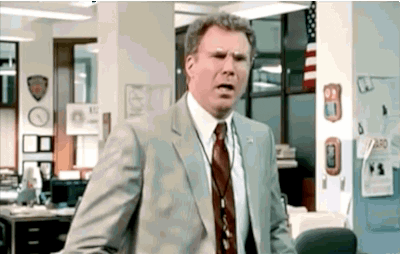 A Man In A Suit And Tie Is Making A Funny Face In An Office . GIF