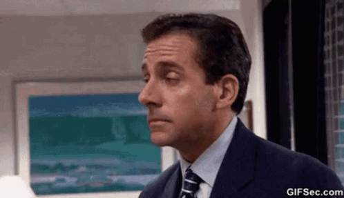 A Man In A Suit And Tie Is Making A Funny Face In An Office . GIF