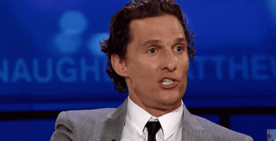 A Man In A Suit And Tie Is Making A Funny Face In Front Of A Sign That Says Laugh At The ! GIF