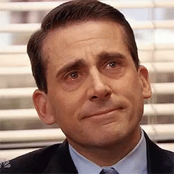 A Man In A Suit And Tie Is Making A Funny Face In Front Of A Window . GIF