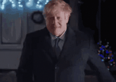 A Man In A Suit And Tie Is Making A Funny Face While Giving A Thumbs Up . GIF