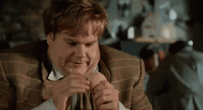 A Man In A Suit And Tie Is Making A Funny Face While Holding His Hand To His Face . GIF