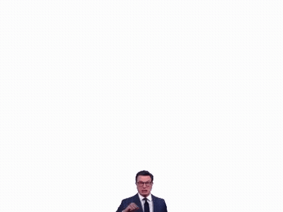 A Man In A Suit And Tie Is Making A Funny Face While Pointing At The Camera . GIF