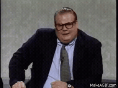 A Man In A Suit And Tie Is Making A Funny Face While Sitting On A Chair . GIF