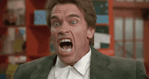 A Man In A Suit And Tie Is Making A Funny Face With His Mouth Open GIF