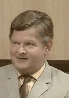 A Man In A Suit And Tie Is Making A Funny Face With His Mouth Open . GIF