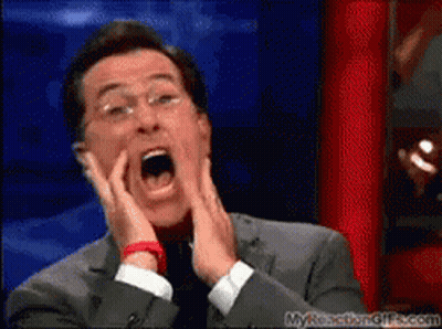 A Man In A Suit And Tie Is Making A Funny Face With His Mouth Open GIF