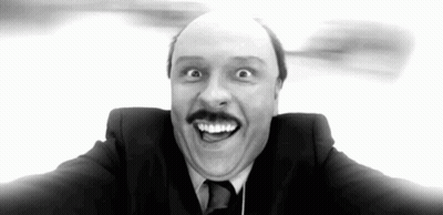 A Man In A Suit And Tie Is Making A Funny Face With His Mouth Open . GIF