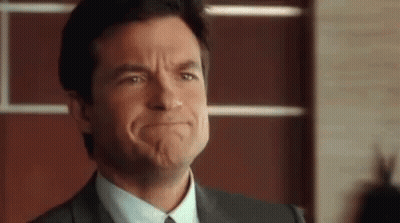 A Man In A Suit And Tie Is Making A Funny Face With His Mouth Open . GIF