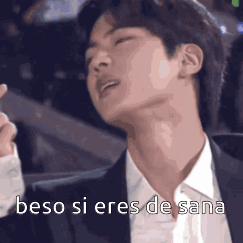 A Man In A Suit And Tie Is Making A Heart Shape With His Finger And Says Beso Si Eres De Sana . GIF
