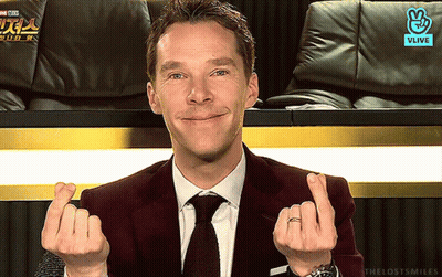 A Man In A Suit And Tie Is Making A Heart With His Hands GIF