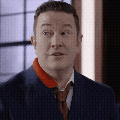 A Man In A Suit And Tie Is Making A Surprised Face . GIF