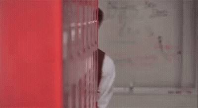 A Man In A Suit And Tie Is Peeking Out From Behind A Red Wall And Says " You Good " GIF