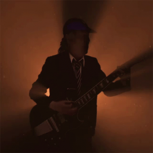 A Man In A Suit And Tie Is Playing A Guitar In A Dark Room GIF