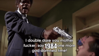 A Man In A Suit And Tie Is Pointing A Gun At Another Man With The Words " I Double Dare You Mother Fucker " Above Him GIF