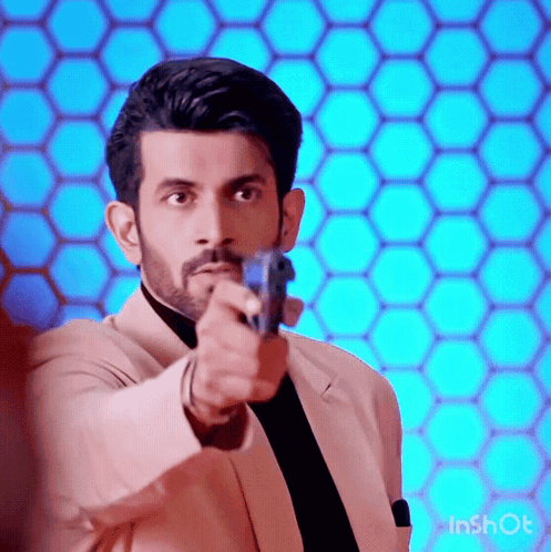 A Man In A Suit And Tie Is Pointing A Gun At Someone . GIF