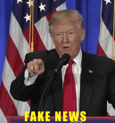A Man In A Suit And Tie Is Pointing At A Microphone With Fake News Written In Yellow GIF