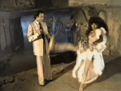 A Man In A Suit And Tie Is Pointing At A Woman In A White Dress GIF
