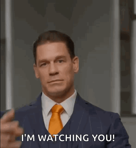 A Man In A Suit And Tie Is Pointing At His Eye And Saying I 'M Watching You . GIF