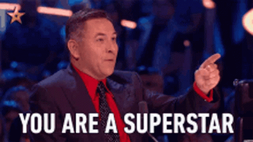 A Man In A Suit And Tie Is Pointing At Someone And Says You Are A Superstar . GIF