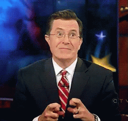 A Man In A Suit And Tie Is Pointing At Something GIF