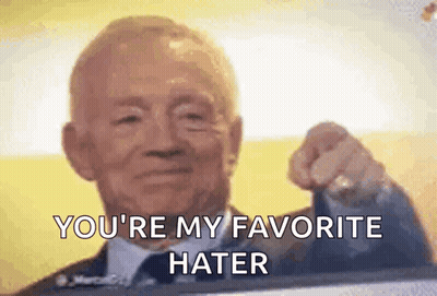 A Man In A Suit And Tie Is Pointing At The Camera . GIF