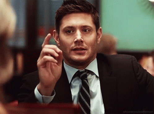 A Man In A Suit And Tie Is Pointing Up GIF